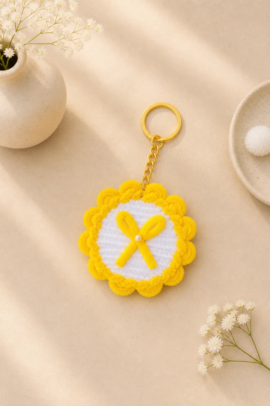 Handmade yellow flower keychain with bow detail and pearl center made from pipe cleaners on soft aesthetic background