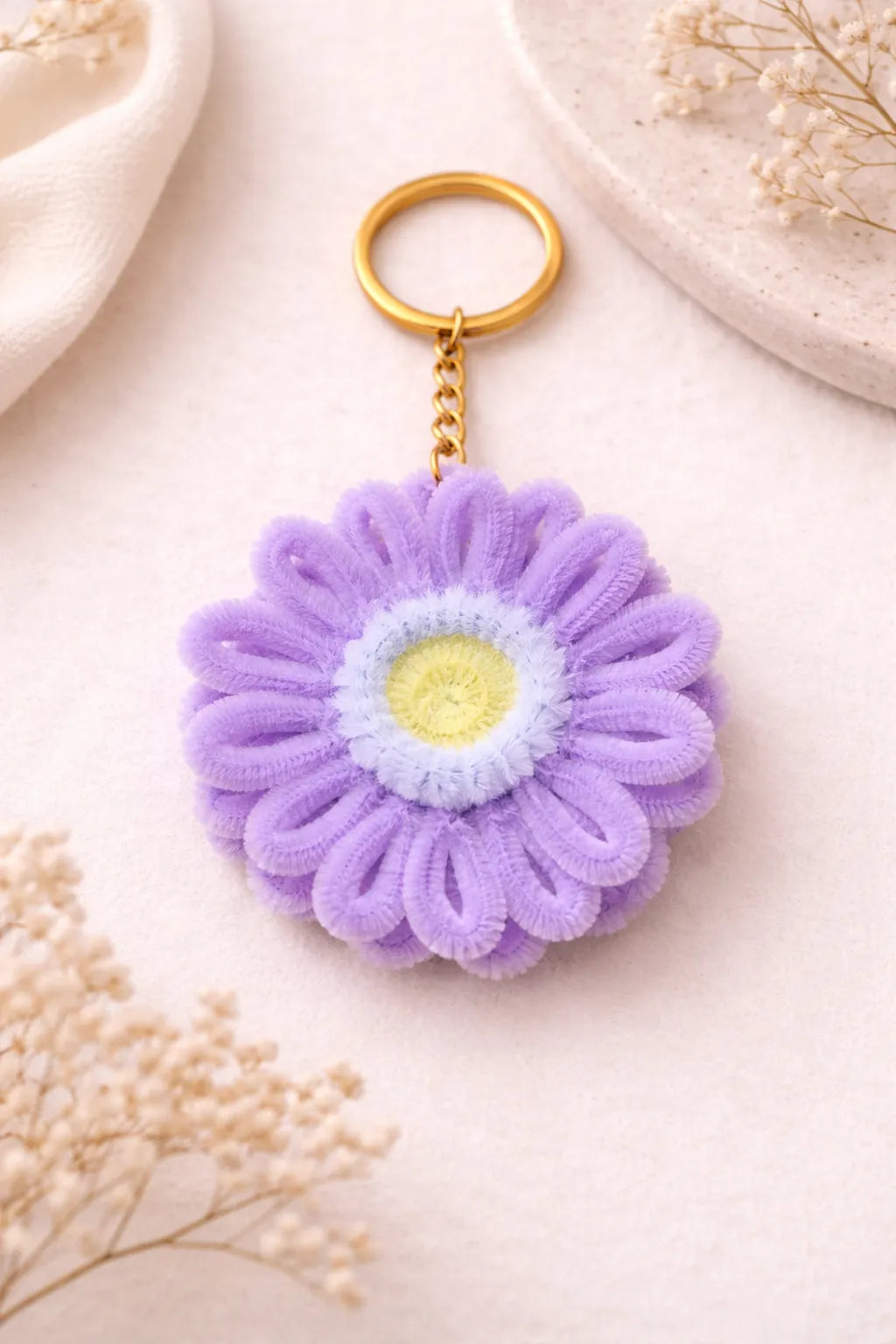 Purple flower-shaped keychain on a light background

